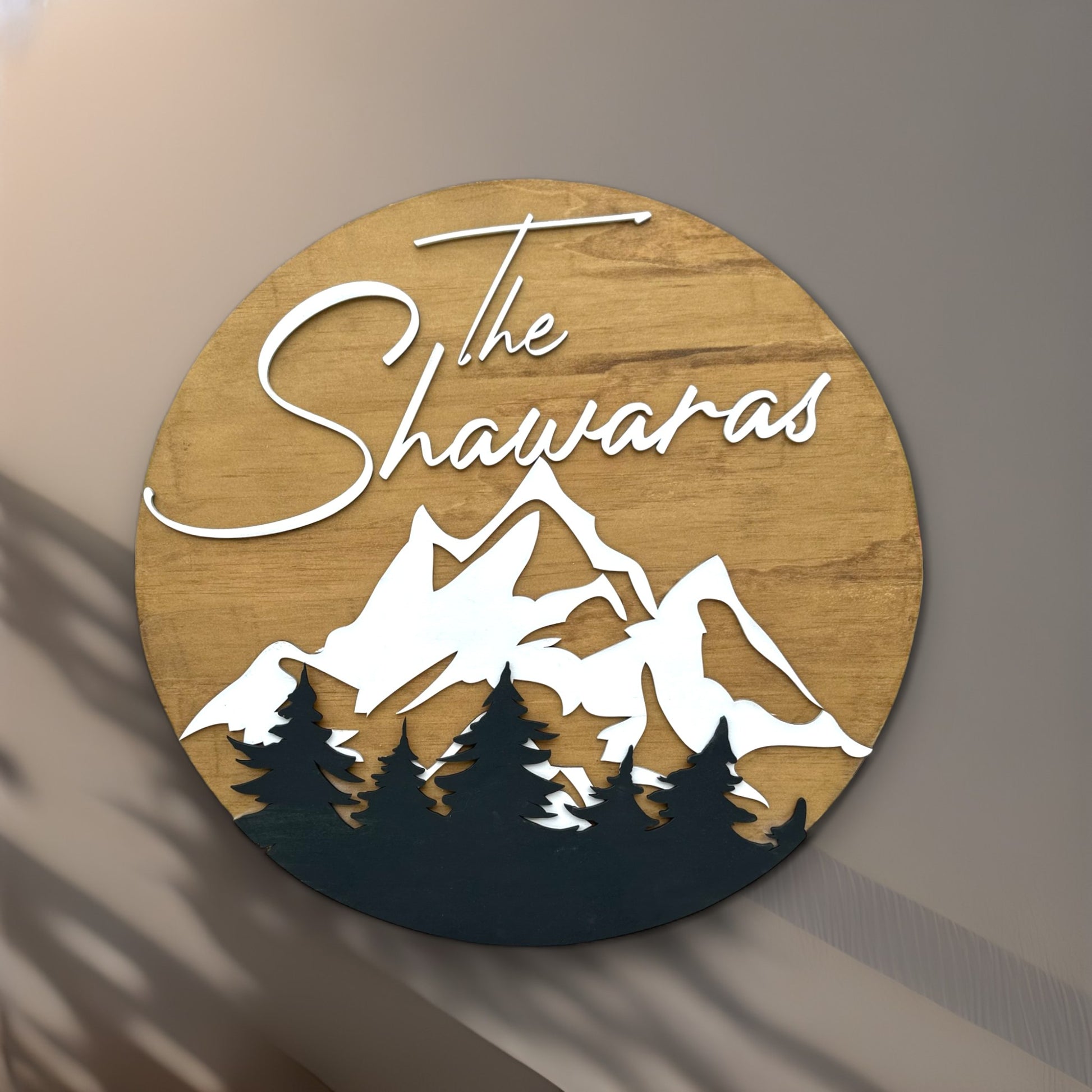 Round wood sign with trees and mountains with last name